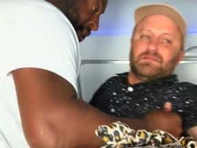Drunk passenger, right, being picked up before being dropped into seat by another traveller on Breeze Airlines flight.