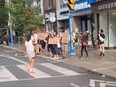 Protesters hold signs on a sidewalk.