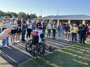 Michigan high school football player Colton Mims is pushed in a wheelchair before a game.