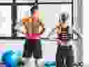 A man and woman experiencing backache after working out in a gym.