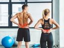 A man and woman experiencing backache after working out in a gym.