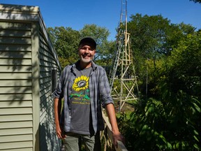 Alex Babich, pose in front of the structure that surrounds his nearly 36-feet high sunflower that holds the world record for the tallest flower at his home in Fort Wayne, Ind., Thursday, Sept. 11, 2025.