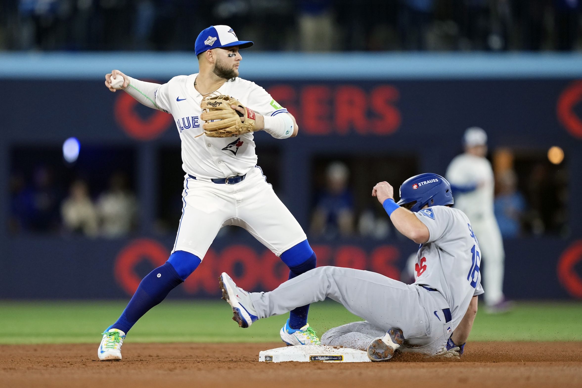 Bo Bichette #11 of the Toronto Blue Jays throws late to first base after displacing Will Smith #16 of the Los Angeles Dodgers at second base in Game 1 of the 2025 World Series at Rogers Center on October 24, 2025 in Toronto.