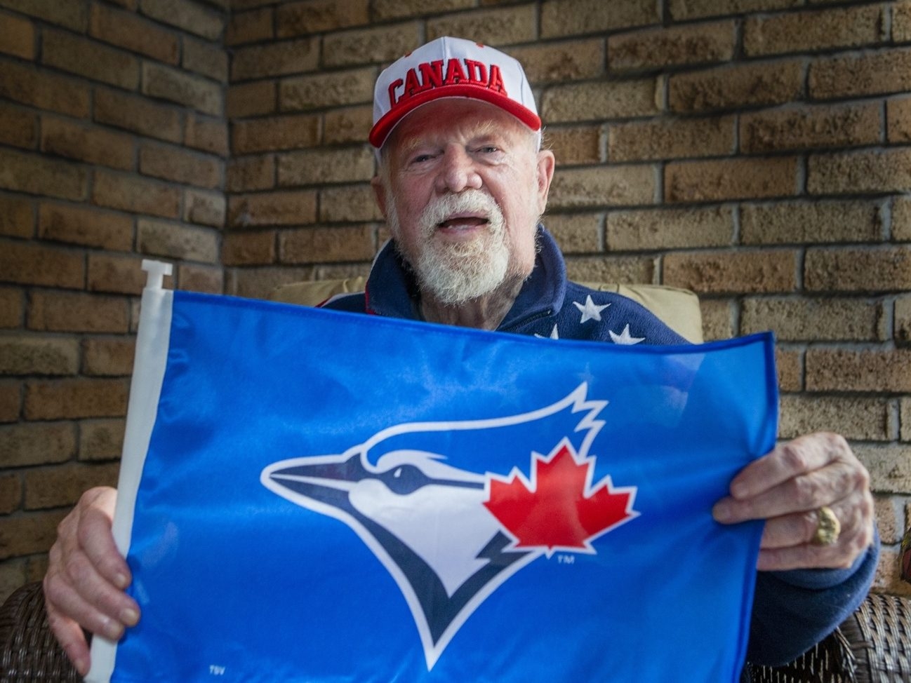 Legendary hockey coach Don Cherry holds up a Toronto Blue Jays flag at his home in Mississauga, Ont., on Monday, Oct. 20, 2025.  Legendary hockey coach Don Cherry holds up a Toronto Blue Jays flag at his home in Mississauga, Ont., on Monday, Oct. 20, 2025.