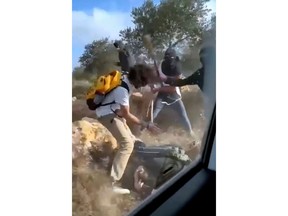 Photo taken on October 19, 2025, shows masked settlers beating activists and Palestinian farmers in Turmus Aya, West Bank. (AP Photo)