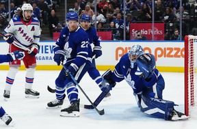 Maple Leafs goaltender Anthony Stolarz (41) makes a save as New York Rangers' Mika Zibanejad (93) and Toronto Maple Leafs' Jake McCabe (22) and Chris Tanev (8) look on during the first period of an NHL hockey game in Toronto on Thursday, October 16. 2025. (THE CANADIAN PRESS/Nathan Denette)