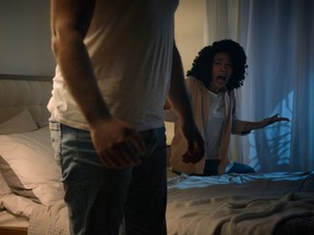 A woman screams at a man as he leaves the bed during a late-night argument.