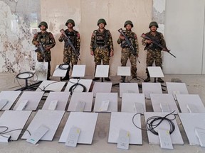 Myanmar soldiers stand next to captured Starlink computers.