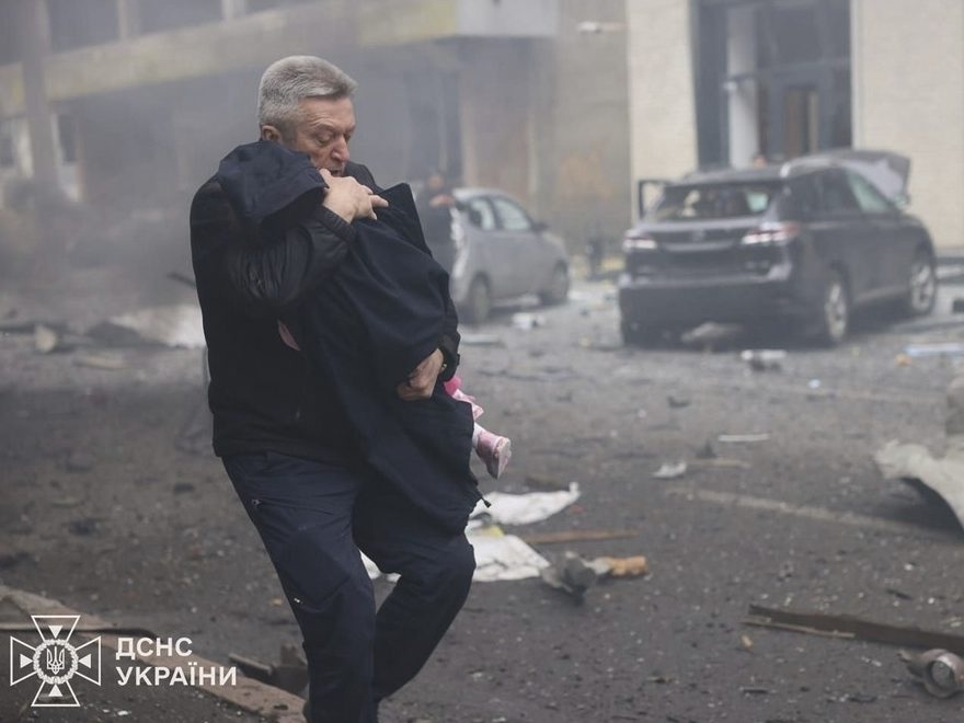 In this photo provided by the Ukrainian Emergency Service, a man evacuates a child after Russian drones hit a city kindergarten in Kharkiv, Ukraine, Wednesday, Oct. 22, 2025. (Ukrainian Emergency Service via AP) In this photo provided by the Ukrainian Emergency Service, a man evacuates a child after Russian drones hit a city kindergarten in Kharkiv, Ukraine, Wednesday, Oct. 22, 2025. (Ukrainian Emergency Service via AP)