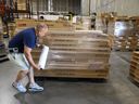 A worker wraps plastic around a pallet of furniture at an import warehouse in Linden, New Jersey.