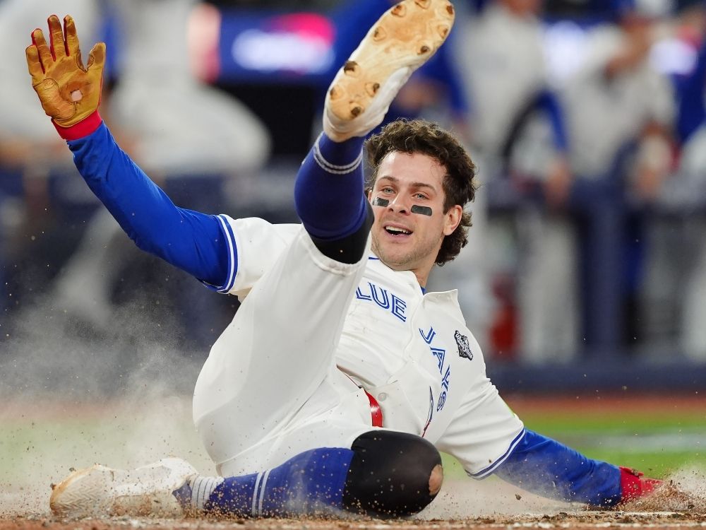 Ernie Clement of the Toronto Blue Jays slides into home plate and scores on Andres Jimenez's double during Game 7 of the World Series.