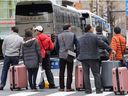 FILE - Chinese tourists wait for a bus at the Tokyo's Ginza shopping district in Tokyo, Saturday, March 12, 2016.