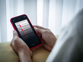 SMS spam and fake text message phishing concept. System hacked warning alert, email hack, scam malware spreading virus alert, notification on mobile phone screen in senior female hands in bedroom.