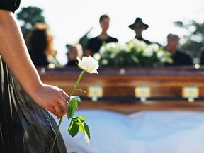 Hand, rose and woman at graveyard for funeral ceremony, grief and memorial service outdoor with family. Flower, death and person by coffin at cemetery for mourning, peace and respect with back view
