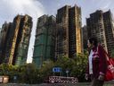 A woman walks past fire-damaged residential buildings at Wan Fuk Court in the Tai Po district of Hong Kong, Friday, November 28, 2025.