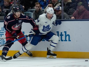 Columbus Blue Jackets defenceman Damon Severson and Toronto Maple Leafs defenceman Morgan Rielly battle for the puck.