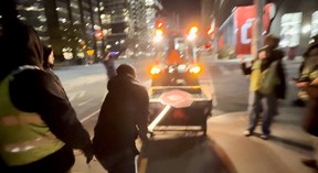 A city-contracted snowplow goes by a Palestinian protest.