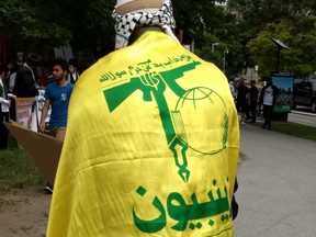 Man wearing Hezbollah flag as a cape in Toronto, June 9, 2018.