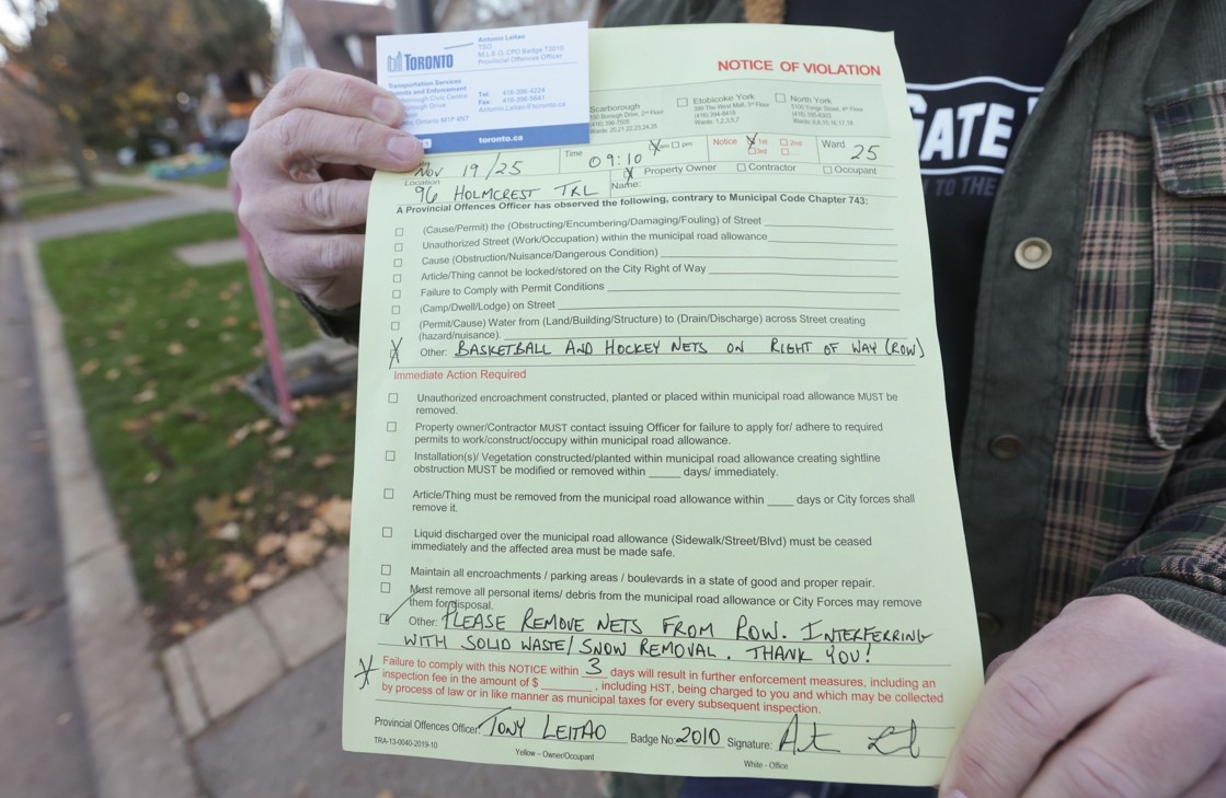  On Nov. 19, a Toronto bylaw officer came to the Scarborough home of Tony Cacciatore (seen here on Thursday, Nov. 20, 2025) who, along with several neighbours, was issued with a Notice of Violation paperwork to move their basketball and hockey nets from the boulevard in front of their homes within three days because it interferes with snow removal and garbage/recycling collection.