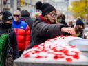 A woman places poppies on the Cenotaph after the Remembrance Day ceremony at the Old Town Hall on November 11, 2025. (Ernest Doroshuk, Toronto Sun)