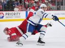 Toronto Maple Leafs' Jacob Quillan checks Detroit Red Wings' Moritz Seider (53) to the ice during a preseason game.