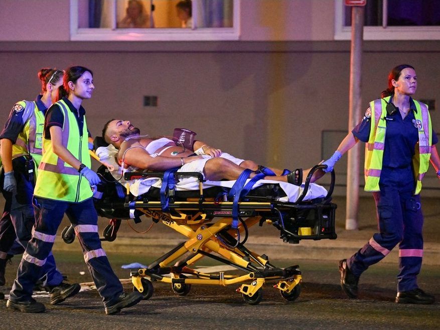 Health workers move a man on a stretcher to an ambulance after a shooting incident at Bondi Beach in Sydney on December 14, 2025.  