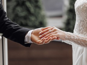 The man gently holds the bride's hand with a beautiful golden wedding ring. Enlarged image of newlyweds' hands. Wedding concept. The groom gently touches the bride