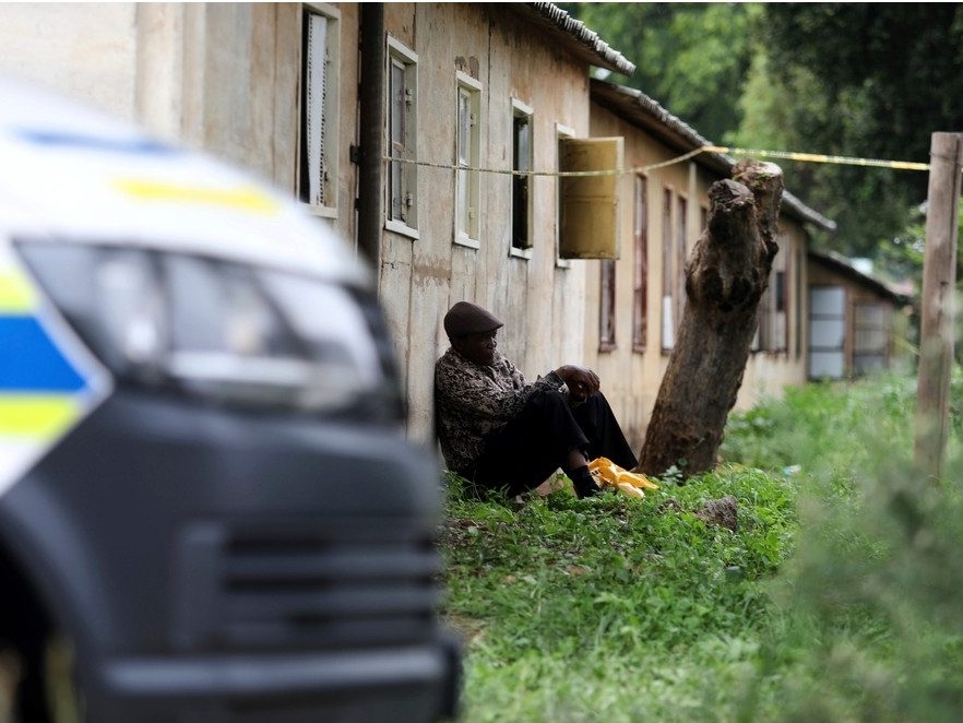  A man sits outside a scene where the bodies of the victims of a mass shooting were found, at a bar near Pretoria, South Africa, Saturday, Dec. 6, 2025.