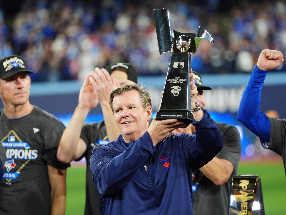 Edward S. Rogers III, chairman of the board of directors of Rogers Communications, holds the ALCS trophy as the Blue Jays celebrate after defeating the Seattle Mariners.