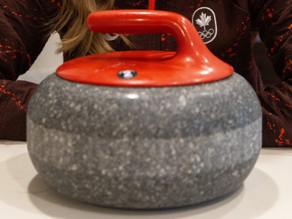 A curling rock with a red handle.