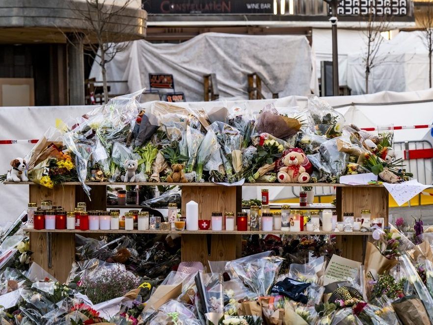 Flowers and candles in tribute to the victims are displayed at a makeshift memorial following a fire at 