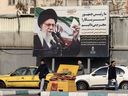 Iranians walk past a billboard showing Iranian supreme leader Ayatollah Ali Khamenei with anti-U.S. rhetoric in Tehran on January 27, 2026.
