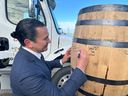 Manitoba Premier Wab Kinew signs barrels outside the Diageo plant where Crown Royal whisky is produced, in Gimli, Man., on Tuesday, Jan. 13, 2026. Kinew is calling on Ontario Premier Doug Ford to cancel a planned boycott of the whisky.