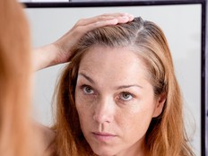 Gray haired woman looking at reflection in morror