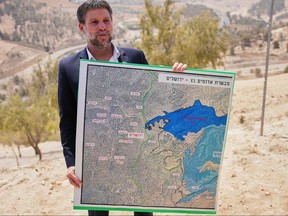 Israeli Finance Minister Bezalel Smotrich holds a map that shows the E1 settlement project.