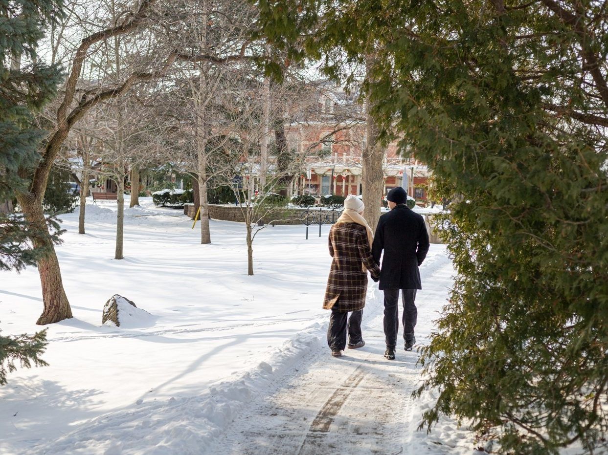 Back of woman and man strolling hand-in-hand along historic neighbourhood in Niagara-on-the-Lake.
