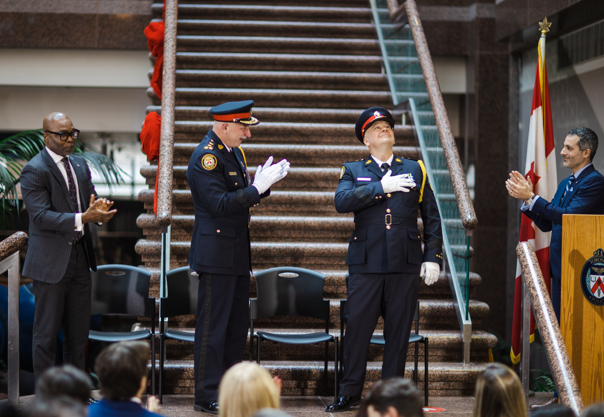  Toronto Police Chief Myron Demkiw (second from right) acknowledges the crowd after completing his oaths of office as TPSB Chair Ainsworth Morgan (far left), former Chief James Ramer (second from left) and then TPSB executive director Ryan Teschner applaud at TPS headquarters on Dec. 19, 2022.