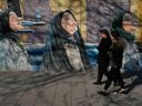 Women walk past a mural at a girls school at Enqelab-e-Eslami, or Islamic Revolution Street, in downtown Tehran, Iran, Wednesday, Feb. 25, 2026.