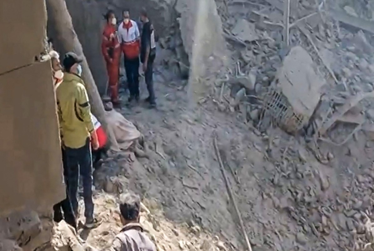  This video grab taken from UGC images posted on social media on Saturday, Feb. 28, 2026, and verified by AFPTV teams in Paris shows people inspecting the damage at an impact site following US and Israeli strikes on Tehran.