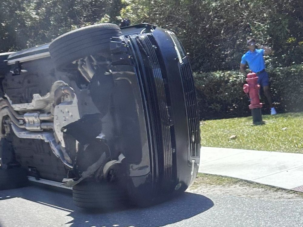 Golfer Tiger Woods stands by his overturned vehicle in Jupiter Island, Fla..