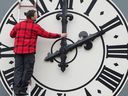 A man adjusts a clock