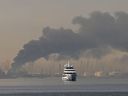 A yacht sails past a plume of smoke rising from the port of Jebel Ali following a reported Iranian strike in Dubai on March 1, 2026.