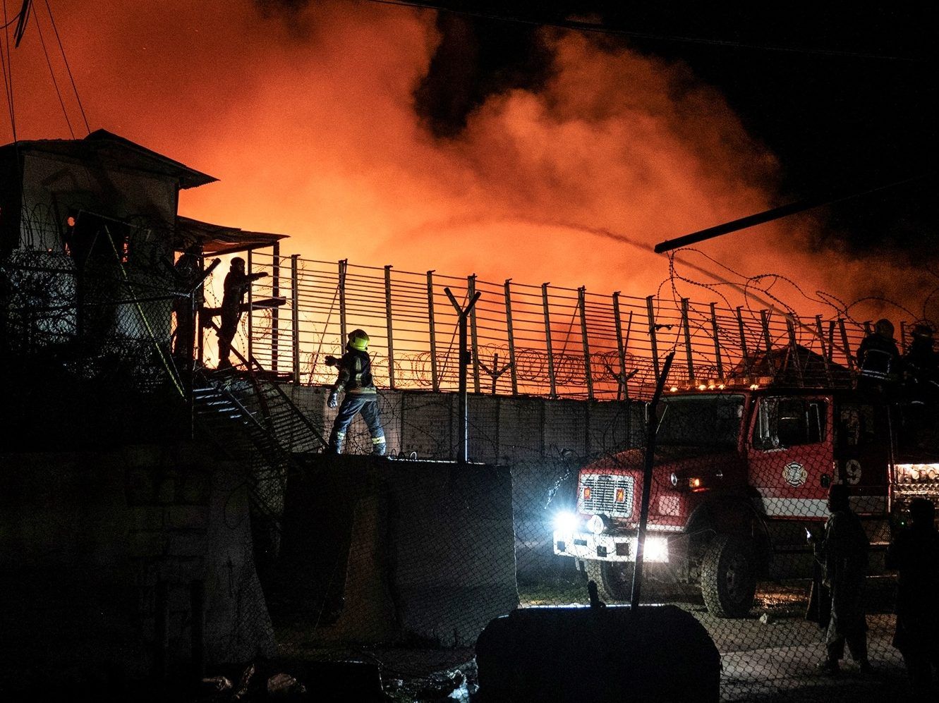 Afghan firefighters and Taliban security personnel work to extinguish a fire.