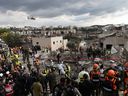 A helicopter flies above as Israeli emergency and rescue personnel work at a direct missile strike site on March 1, 2026 in Beit Shemesh, Israel.