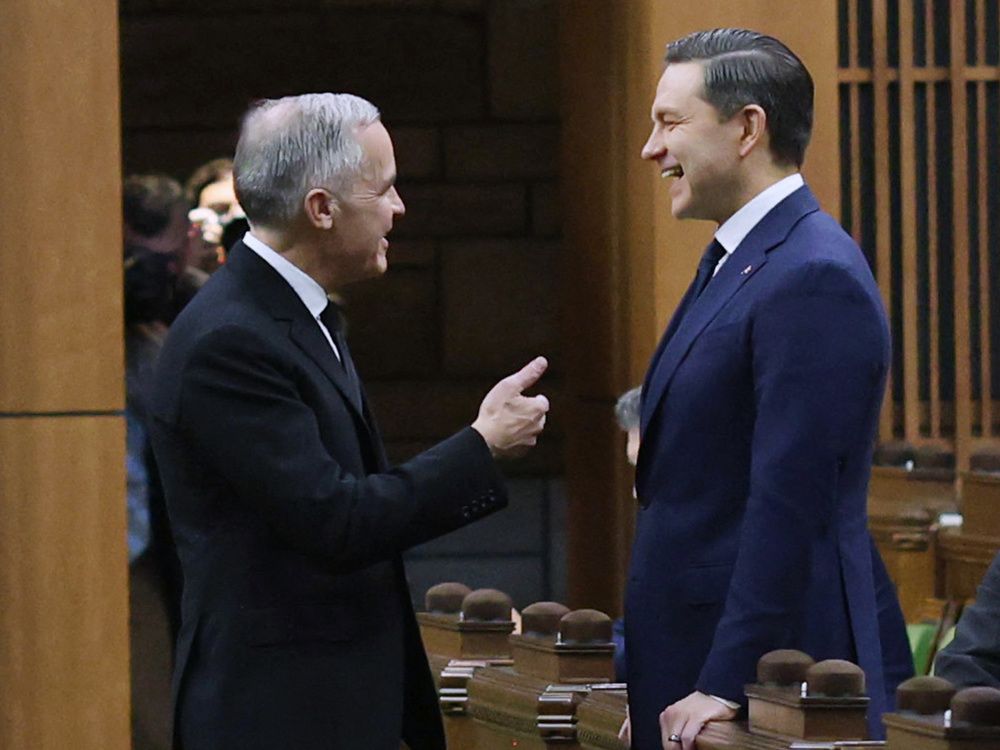 Canada's Prime Minister Mark Carney (L) speaks with Conservative Party leader Pierre Poilievre (R) in the House of Commons on Parliament Hill February 11, 2026 in Ottawa, Ontario. 