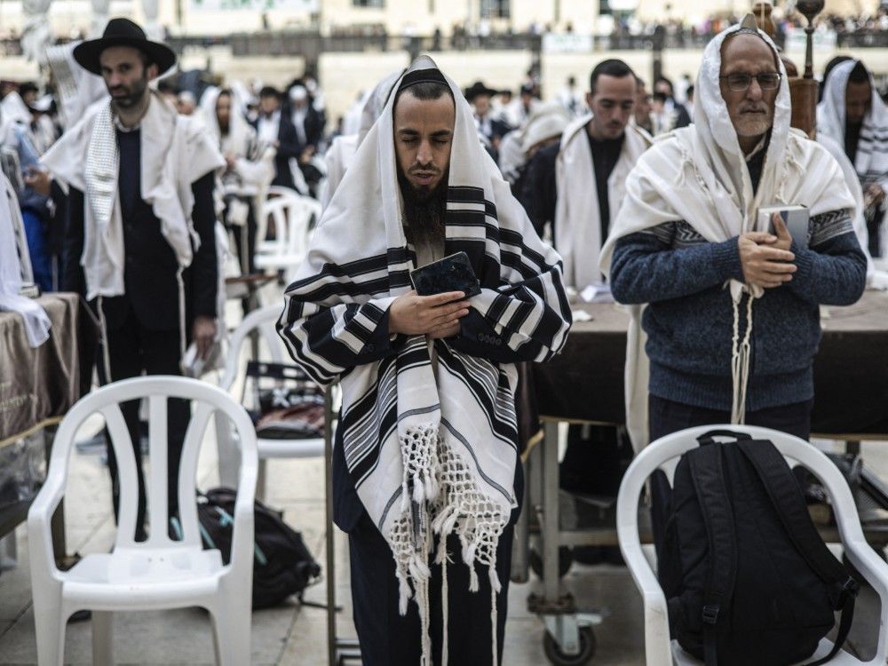 Jewish worshippers wearing traditional prayer shawls known as Tallit take part in the Cohanim prayer during Passover at the Western Wall in the Old City of Jerusalem, April 15, 2025.