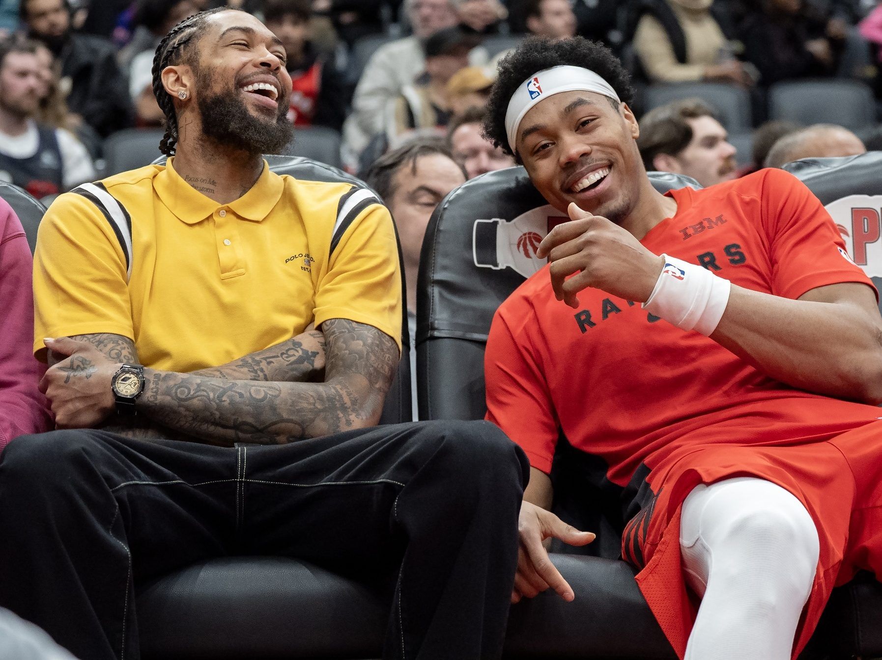 Toronto Raptors' Brandon Ingram and Scottie Barnes share a laugh on the bench during a game.