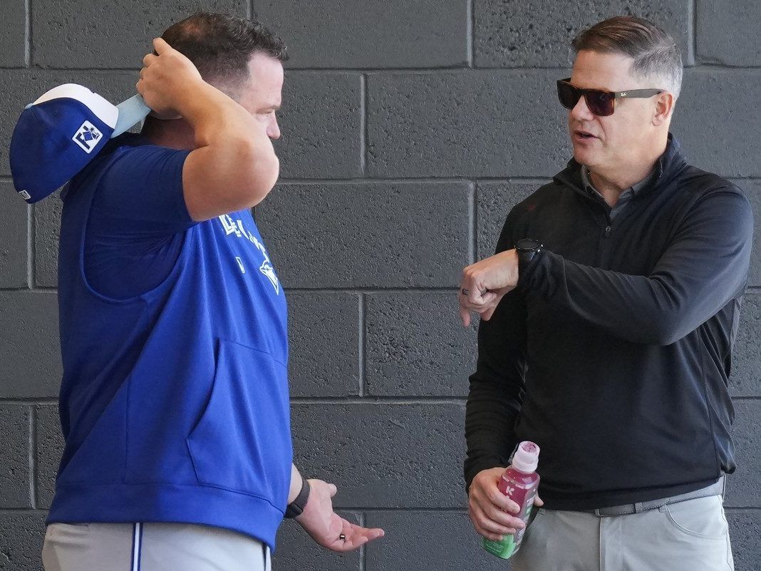 Toronto Blue Jays manager John Schneider, left, talks with Blue Jays general manager Ross Atkins, right, as players work out during spring training in Dunedin Fla., on Friday, February 14, 2025.
