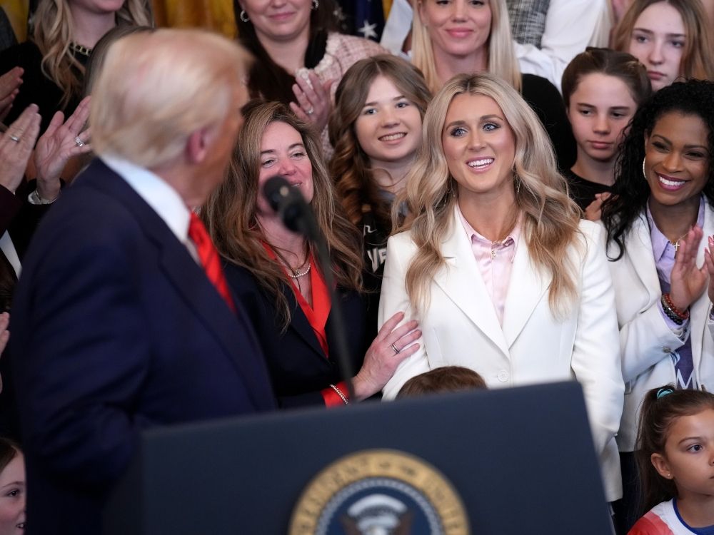Political activist and former competitive swimmer Riley Gaines watches as U.S. President Donald Trump delivers remarks at a press conference in 2025.
