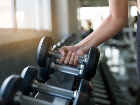 Hand of athlete woman holding dumbbell from the rack in the gym. Muscular fitness female exercise with dumbbell in the gym sport. Concept for exercising fitness and healthy lifestyle workout